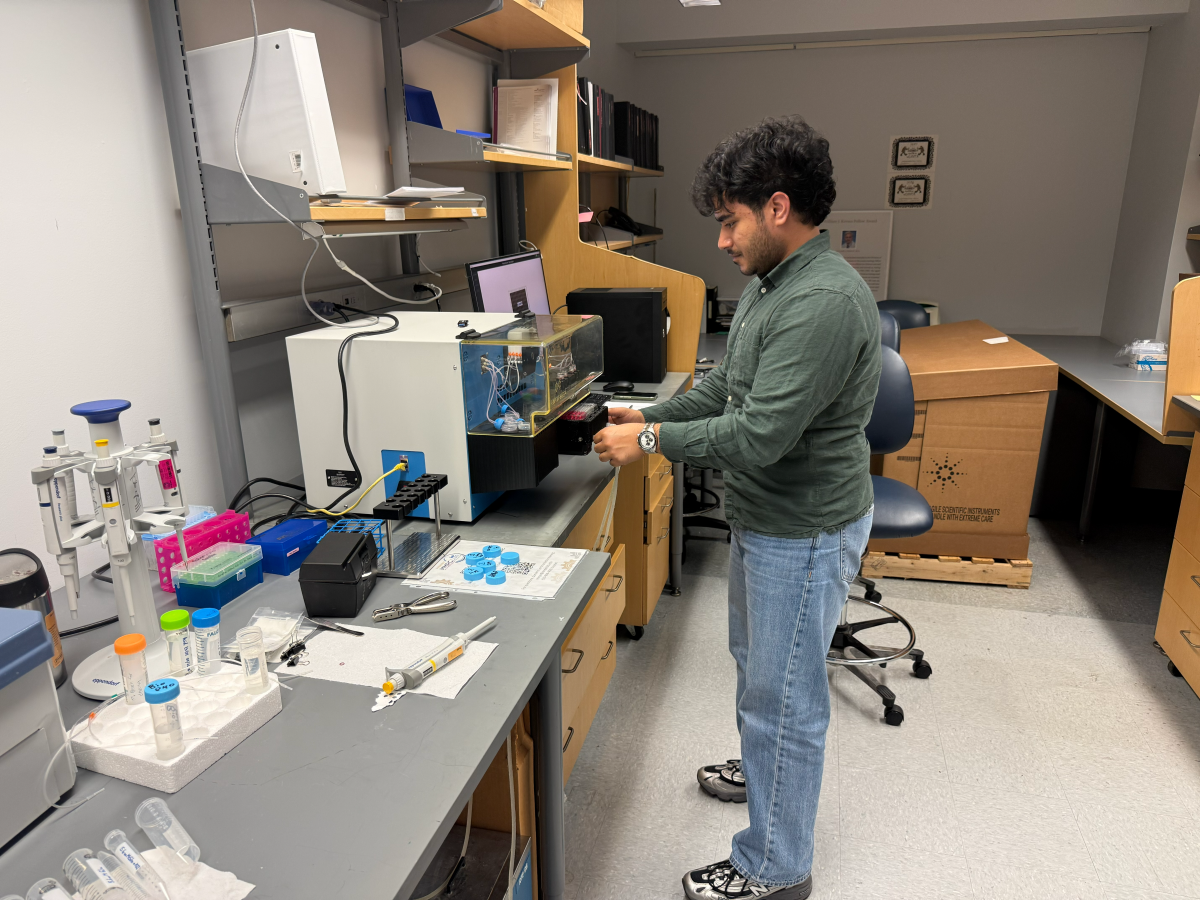 A young researcher in a green shirt and jeans works in the diabetes core.