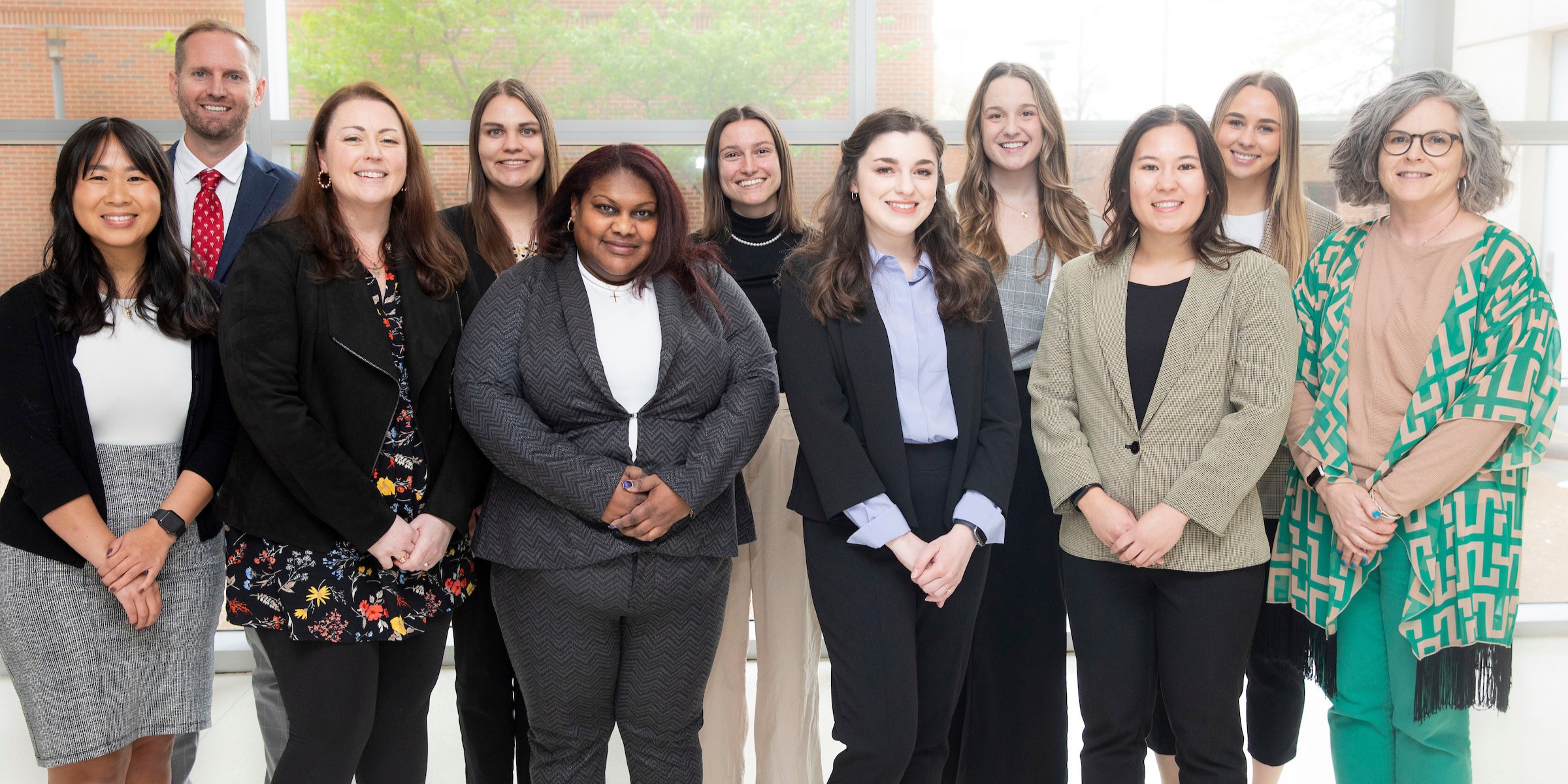 A group of about a dozen genetic counselors, mostly women in business attire, pose for a photo. 