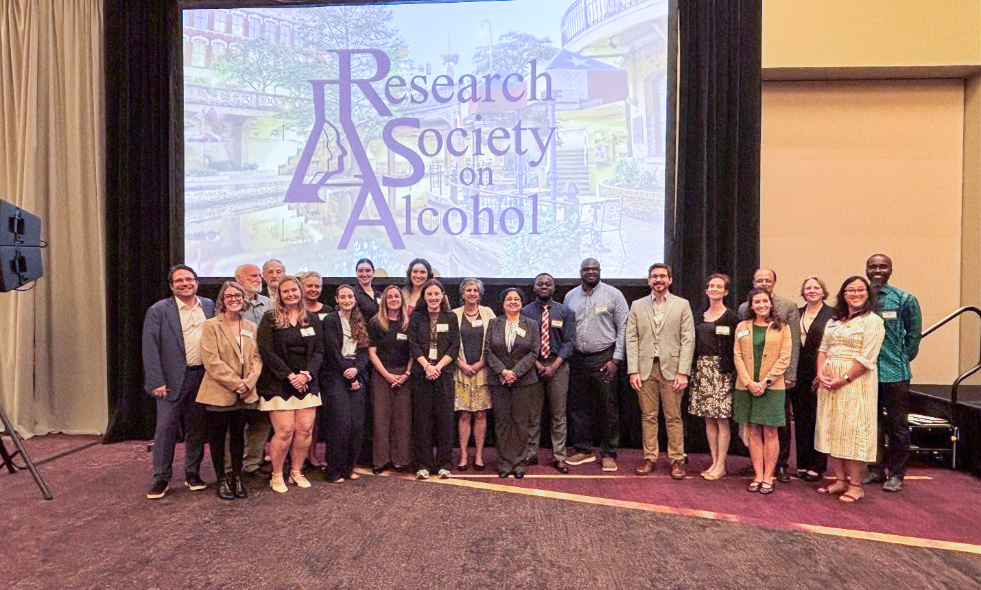 About 2 dozen Research Society on Alcohol meeting participants pose in an auditorium.