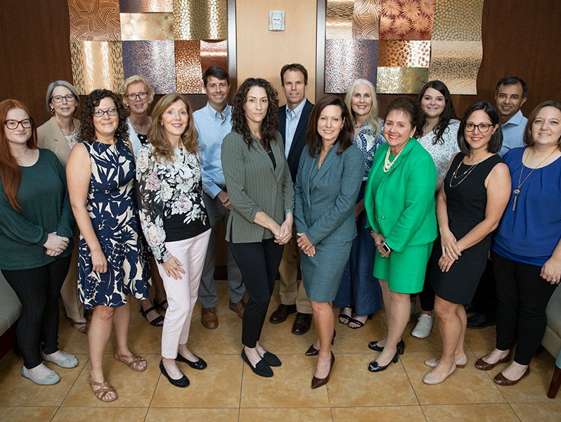 The researchers include a group of about 16 professionally dressed women and a few men.