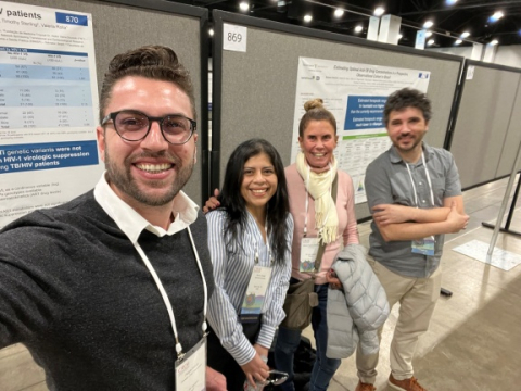 A group of research scientist poses in front of academic posters at the CROI conference.