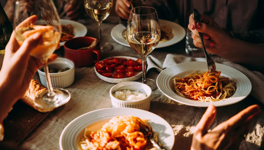 A dinner table with Italian food and white wine.